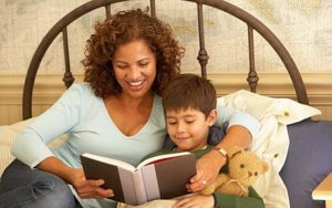 Mother reading to son (6-7) lying in bed
