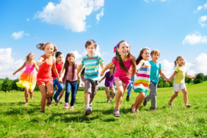 Many different kids, boys and girls running in the park on sunny summer day in casual clothes